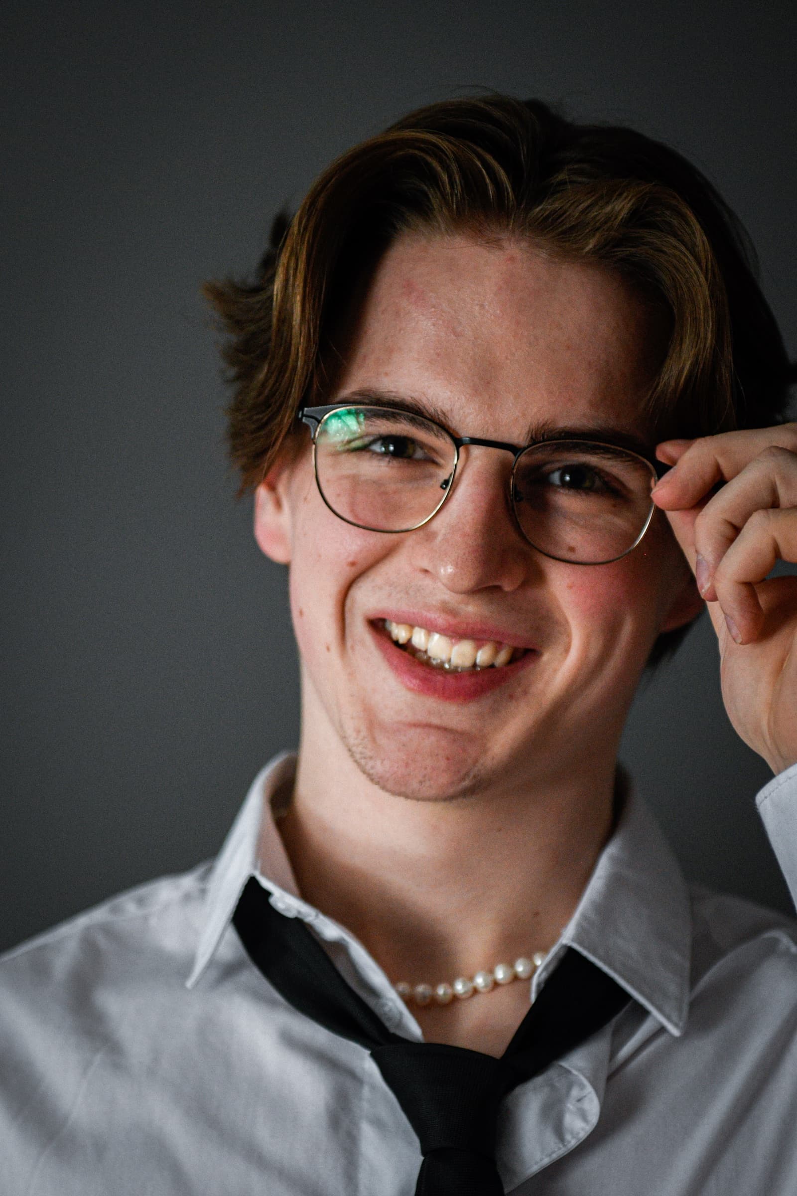 Caeden Smilde in a white shirt and black tie, adjusting his glasses