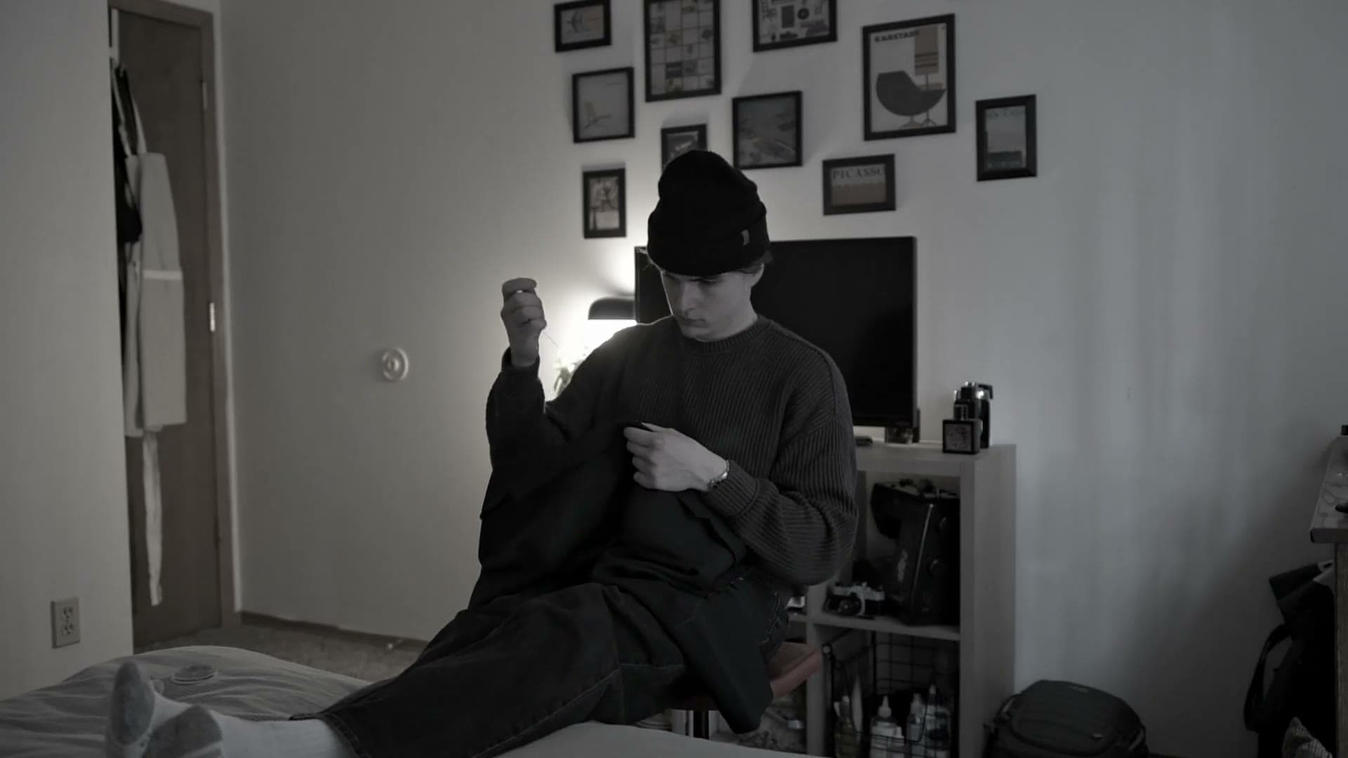 Black and white still showing an open sketchbook of garment croquis beside a pen