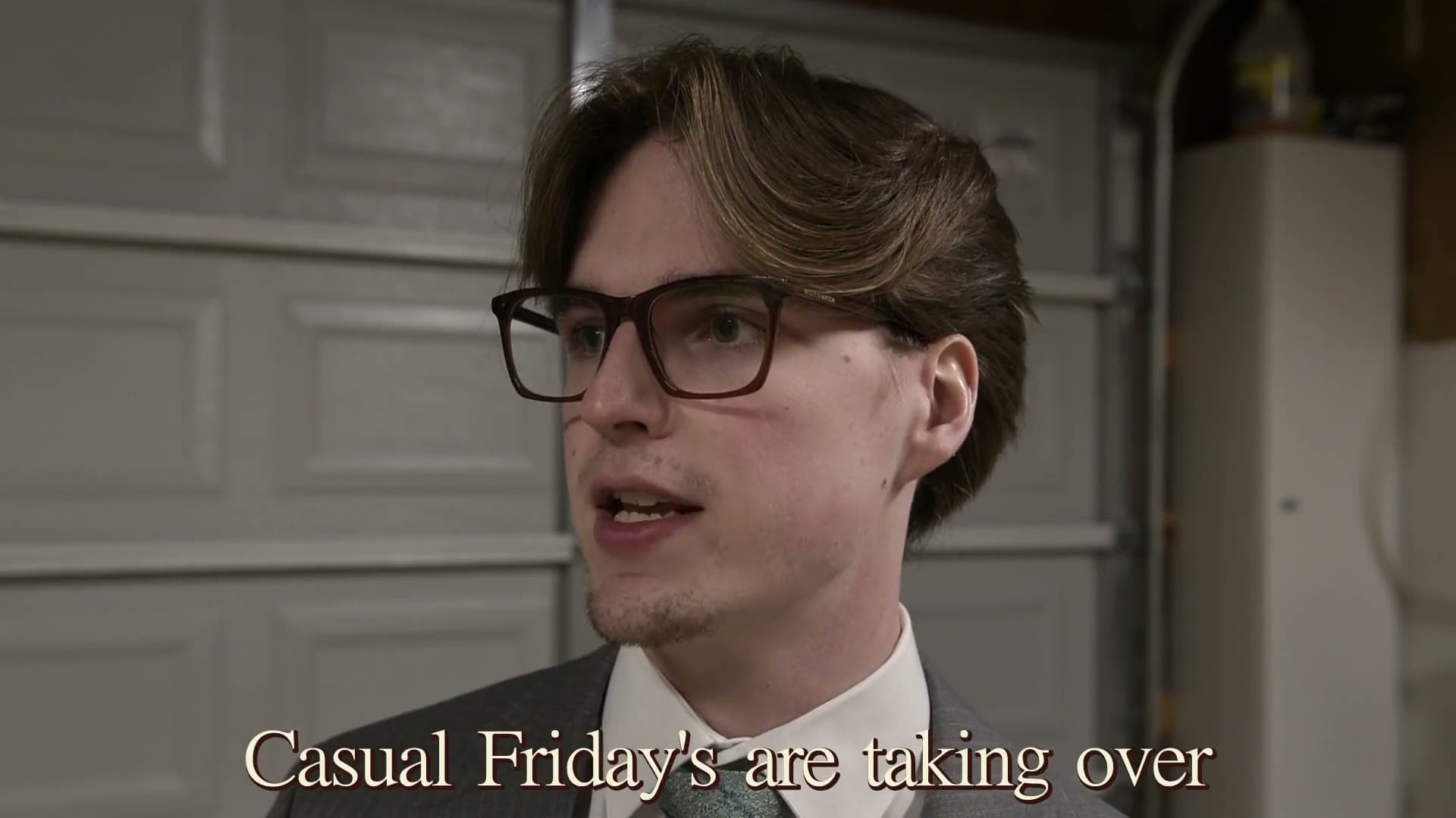 Still from the purSUIT film: a character in a grey checked suit and green tie, mid-scene